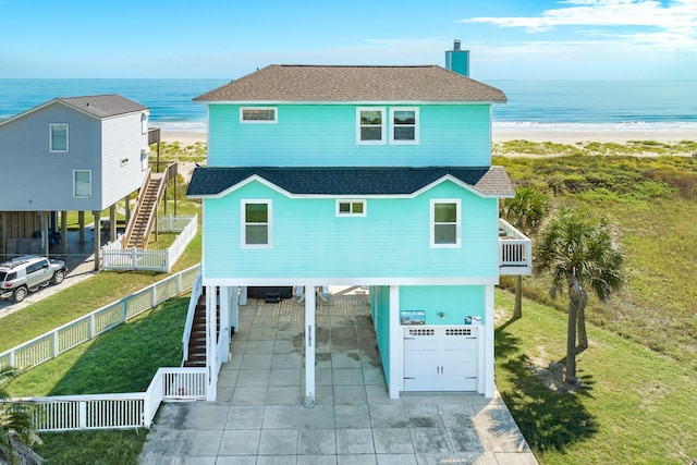 22831 Gulf Dr, Galveston, TX 77554 - view of front of property with stairway, a carport, roof with shingles, a garage, and view of water and beach