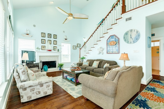 22831 Gulf Dr, Galveston, TX 77554 - living room with a high ceiling, dark wood finished floors, ceiling fan, a fireplace with flush hearth, and stairs