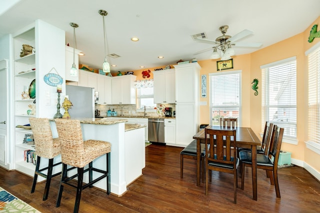 22831 Gulf Dr, Galveston, TX 77554 - kitchen featuring stainless steel dishwasher, a peninsula, a ceiling fan, dark wood finished floors, and light stone countertops