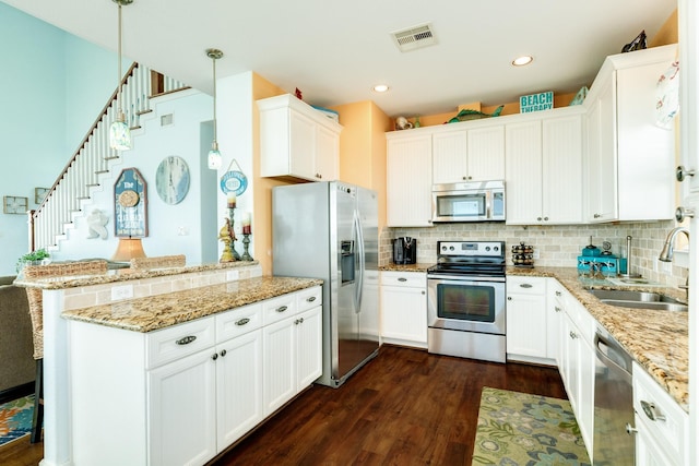 22831 Gulf Dr, Galveston, TX 77554 - kitchen featuring appliances with stainless steel finishes, a peninsula, dark wood-style floors, tasteful backsplash, and recessed lighting