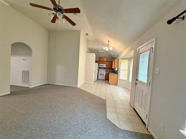 1140 Thomas Dr, Angleton, TX 77515 - unfurnished living room with light tile patterned flooring, vaulted ceiling, a ceiling fan, arched walkways, and light carpet
