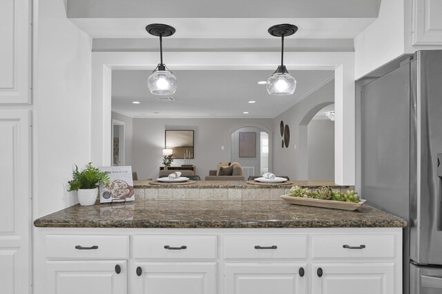 4310 Wigton Dr, Houston, TX 77096 - kitchen featuring freestanding refrigerator, arched walkways, white cabinetry, pendant lighting, and dark stone counters