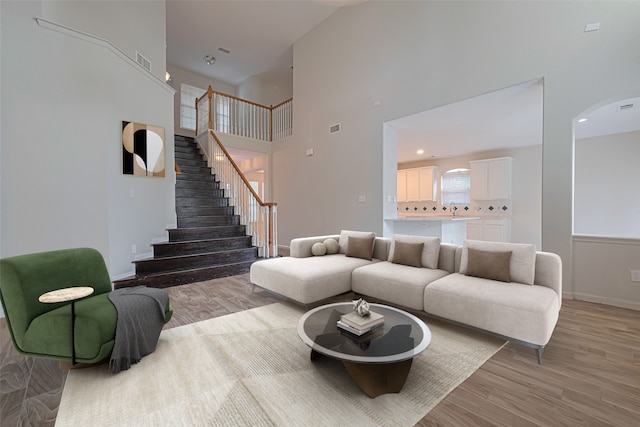 10210 Squirehill Ct, Houston, TX 77070 - living room with stairway, light wood-style floors, a high ceiling, and arched walkways