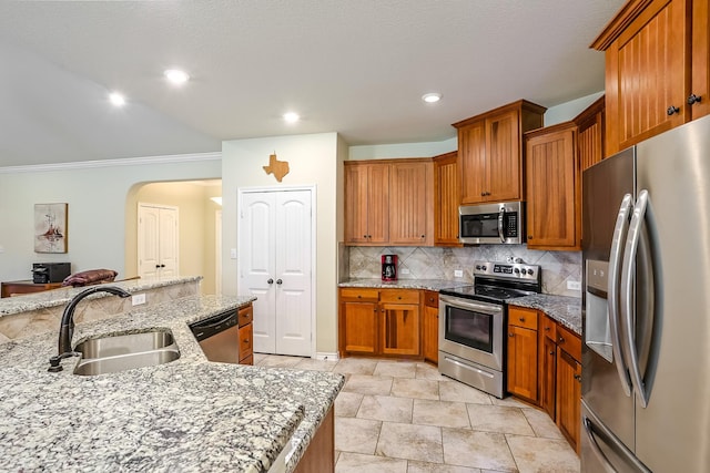 130 Canary Ln, Coldspring, TX 77331 - kitchen with stainless steel appliances, backsplash, crown molding, brown cabinetry, and light stone counters
