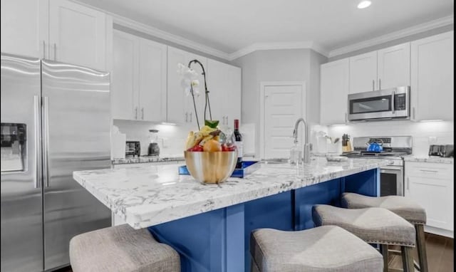 6617 Del Rio St Unit D, Houston, TX 77021 - kitchen featuring stainless steel appliances, white cabinetry, ornamental molding, a breakfast bar area, and light stone countertops