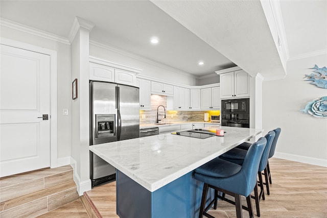 3114 Canterbury Ln, Montgomery, TX 77356 - kitchen featuring black appliances, ornamental molding, a kitchen bar, light stone counters, and tasteful backsplash