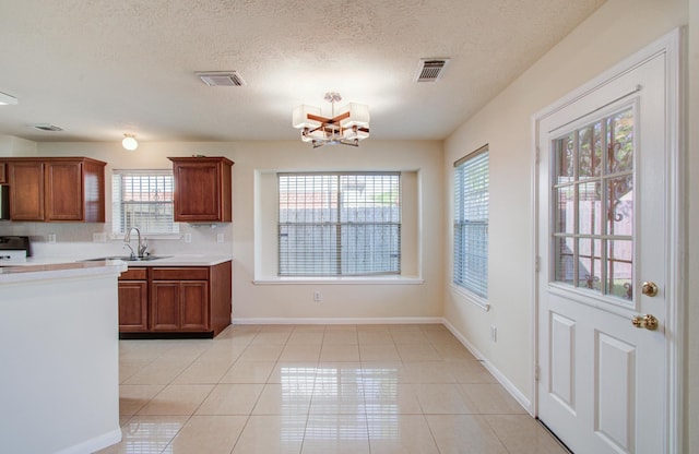 5330 Imperial Grove Dr, Houston, TX 77066 - kitchen with light countertops, light tile patterned floors, brown cabinets, a chandelier, and a textured ceiling
