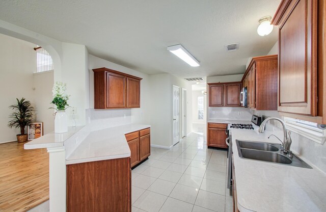 5330 Imperial Grove Dr, Houston, TX 77066 - kitchen with a peninsula, stainless steel microwave, light countertops, range with gas cooktop, and light tile patterned flooring