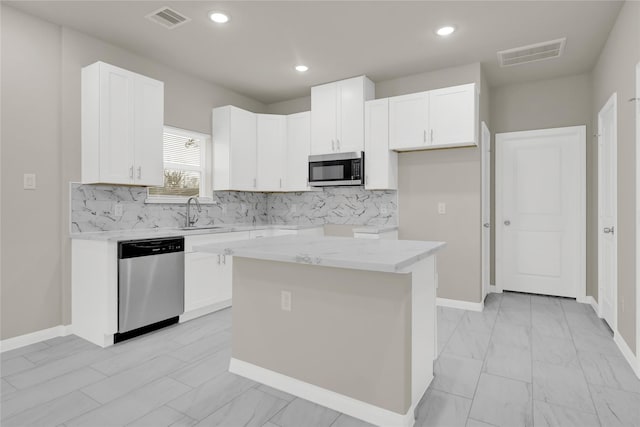 8004 Birmingham St A/B, Unit A/B Houston, TX 77028 - kitchen featuring stainless steel appliances, white cabinets, decorative backsplash, light stone countertops, and a kitchen island