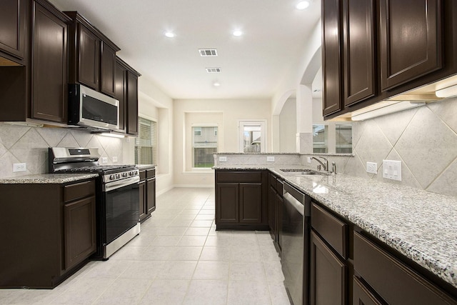 2311 Langley Dr, Rosharon, TX 77583 - kitchen with stainless steel appliances, light stone countertops, decorative backsplash, dark brown cabinetry, and recessed lighting