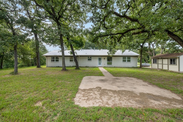 73 Fairway Dr, Normangee, TX 77871 - back of property featuring a metal roof, a lawn, a storage unit, and a patio area