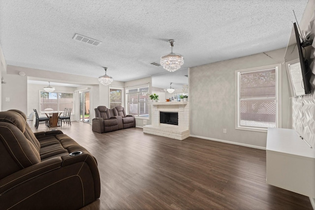 9827 Gold Cup Way, Houston, TX 77065 - living area with a chandelier, dark wood-style flooring, a textured ceiling, and a brick fireplace
