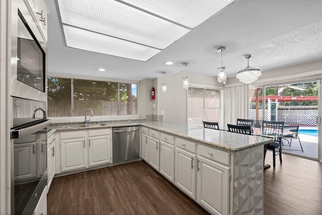 9827 Gold Cup Way, Houston, TX 77065 - kitchen featuring stainless steel appliances, dark wood-style floors, a peninsula, white cabinets, and recessed lighting