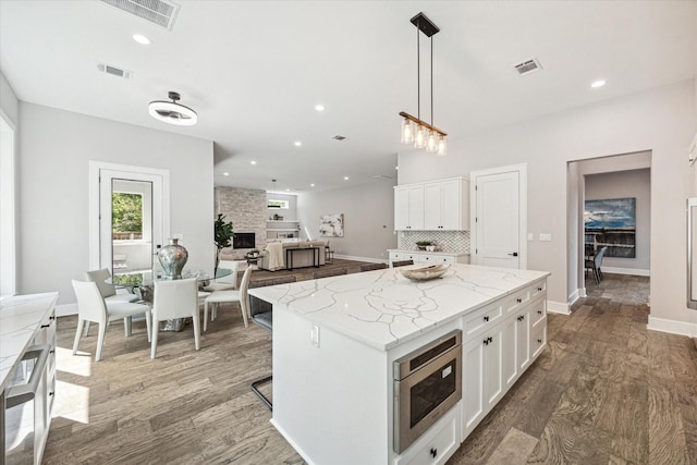 2065 Southgate Blvd, Houston, TX 77030 - kitchen with stainless steel microwave, white cabinetry, wood finished floors, and recessed lighting