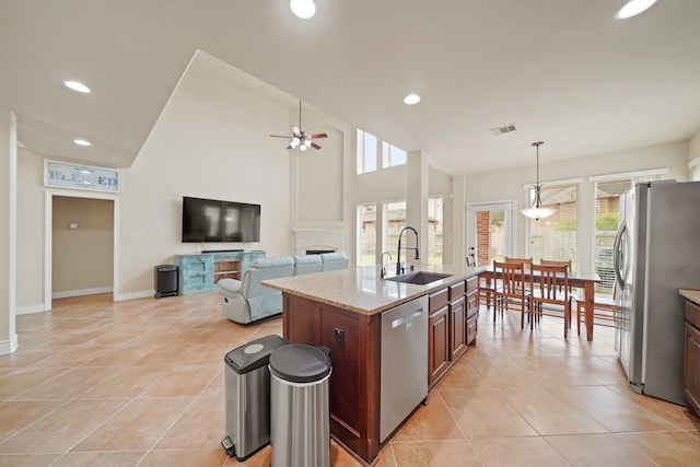 19831 Indigo Key Ct, Cypress, TX 77433 - kitchen with appliances with stainless steel finishes, ceiling fan, light tile patterned flooring, light stone counters, and a center island with sink