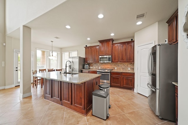 19831 Indigo Key Ct, Cypress, TX 77433 - kitchen featuring stainless steel appliances, decorative backsplash, light tile patterned floors, an island with sink, and light stone counters