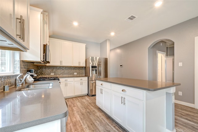 11442 Harmony Summit Trce, Richmond, TX 77406 - kitchen featuring stainless steel fridge, light wood finished floors, arched walkways, decorative backsplash, and recessed lighting