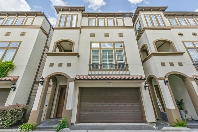 6107 Stillman St, Houston, TX 77007 - view of front of home featuring a garage, a balcony, driveway, and stucco siding