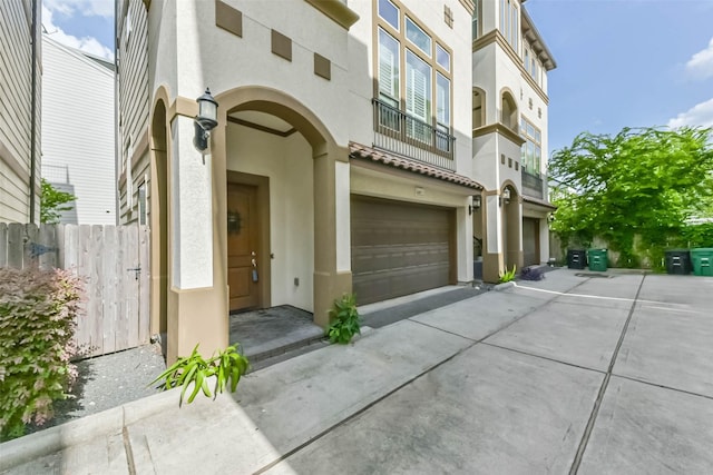 6107 Stillman St, Houston, TX 77007 - view of exterior entry with stucco siding, driveway, an attached garage, and a balcony