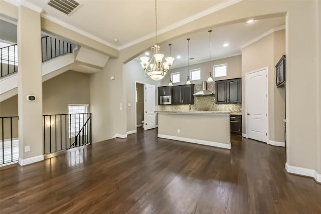 6107 Stillman St, Houston, TX 77007 - kitchen with a chandelier, stainless steel microwave, dark wood-style flooring, decorative backsplash, and a center island with sink
