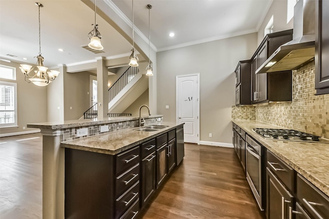 6107 Stillman St, Houston, TX 77007 - kitchen with wall chimney range hood, appliances with stainless steel finishes, an island with sink, dark brown cabinetry, and ornamental molding