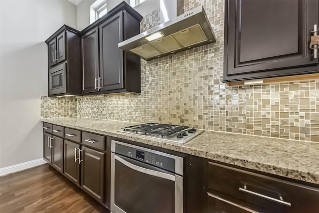 6107 Stillman St, Houston, TX 77007 - kitchen with appliances with stainless steel finishes, wall chimney range hood, decorative backsplash, light stone counters, and dark brown cabinetry
