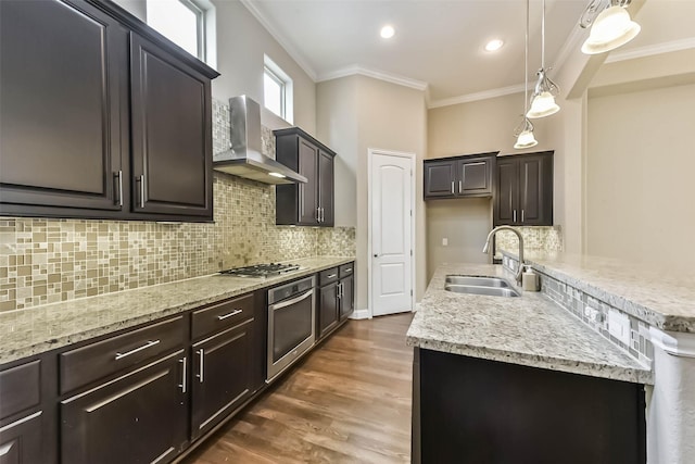 6107 Stillman St, Houston, TX 77007 - kitchen featuring wall chimney exhaust hood, stainless steel appliances, crown molding, an island with sink, and backsplash