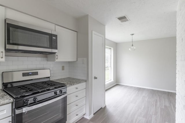 15803 Cerca Blanca Dr, Houston, TX 77083 - kitchen featuring range with gas stovetop, stainless steel microwave, wood finished floors, a textured ceiling, and white cabinets
