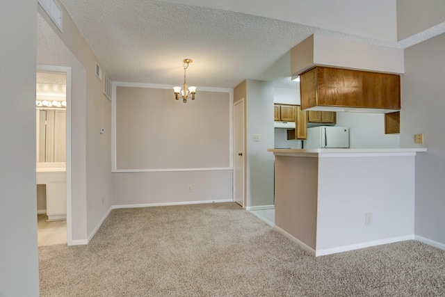 12550 Whittington Dr Unit 610, Houston, TX 77077 - kitchen with freestanding refrigerator, a chandelier, light colored carpet, brown cabinetry, and a textured ceiling