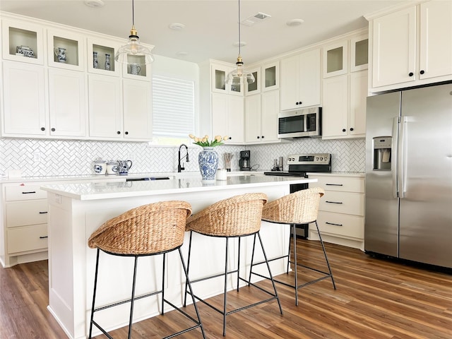2263 Lcr 740, Thornton, TX 76687 - kitchen featuring appliances with stainless steel finishes, dark wood-style floors, tasteful backsplash, a center island, and a kitchen bar