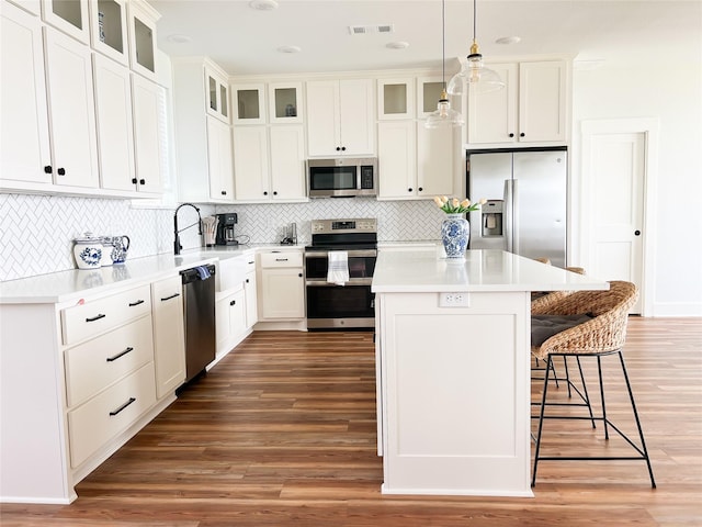 2263 Lcr 740, Thornton, TX 76687 - kitchen featuring appliances with stainless steel finishes, a kitchen island, a breakfast bar area, wood finished floors, and tasteful backsplash