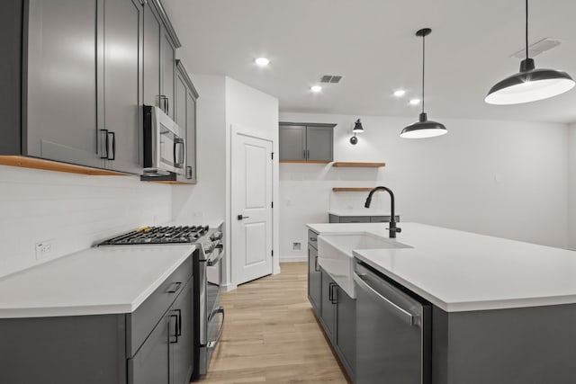 8410 Bay Oaks Dr, Baytown, TX 77523 - kitchen featuring stainless steel appliances, light wood-style flooring, a kitchen island with sink, light countertops, and tasteful backsplash