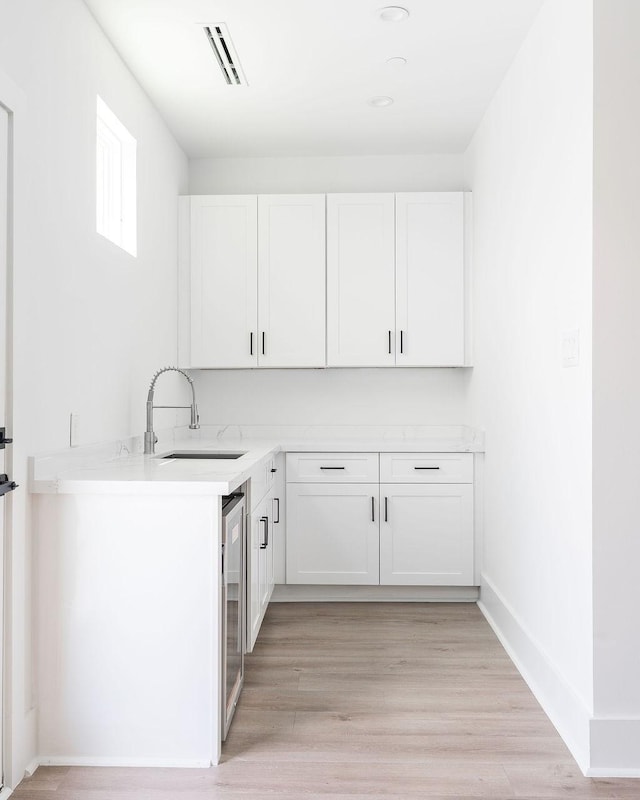 5703 Dolores St Unit A, Houston, TX 77057 - kitchen featuring white cabinetry, light countertops, wine cooler, and light wood-style flooring