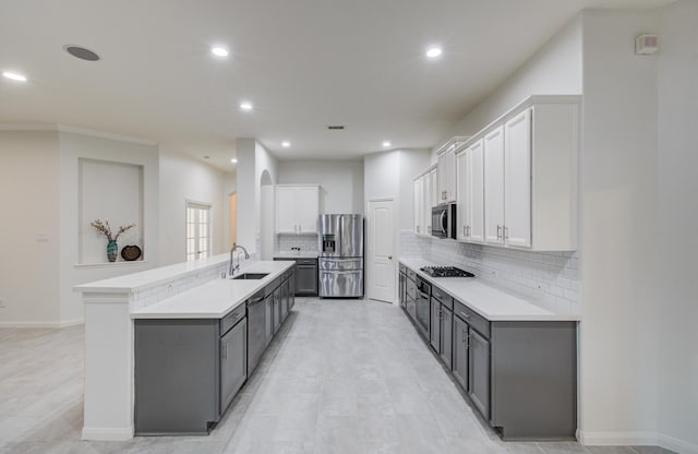 4639 Regal Shadow Ln, Sugar Land, TX 77479 - kitchen with stainless steel appliances, backsplash, white cabinets, a center island with sink, and gray cabinets