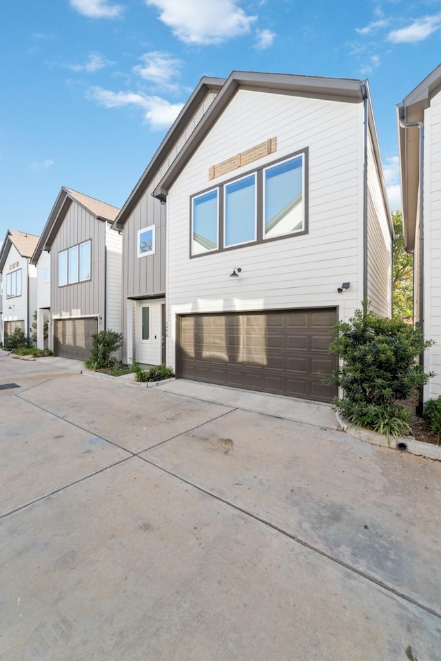 240 Julia St Unit D, Houston, TX 77022 - view of front of house featuring board and batten siding, driveway, and a garage
