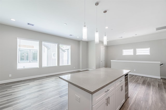 240 Julia St Unit D, Houston, TX 77022 - kitchen featuring open floor plan, light wood-style flooring, white cabinetry, a center island, and pendant lighting