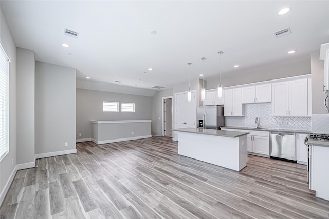 240 Julia St Unit D, Houston, TX 77022 - kitchen featuring appliances with stainless steel finishes, a center island, backsplash, open floor plan, and white cabinets