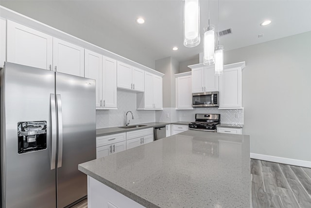 240 Julia St Unit D, Houston, TX 77022 - kitchen with stainless steel appliances, light wood finished floors, a kitchen island, white cabinets, and tasteful backsplash