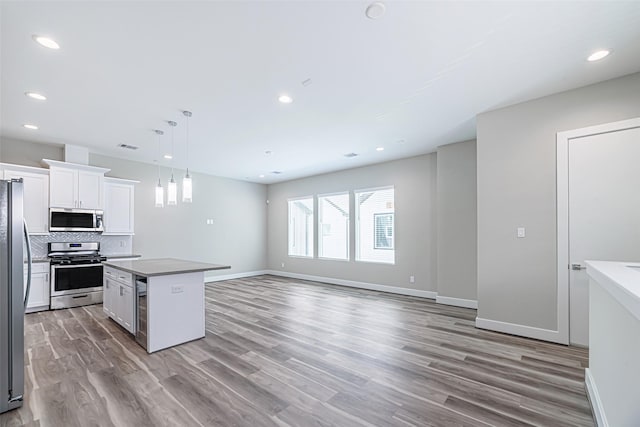 240 Julia St Unit D, Houston, TX 77022 - kitchen with appliances with stainless steel finishes, light wood-style floors, a center island, decorative backsplash, and recessed lighting