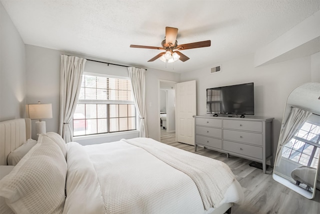 2300 Old Spanish Trl Unit 1060, Houston, TX 77054 - bedroom featuring light wood finished floors, radiator heating unit, a ceiling fan, and a textured ceiling