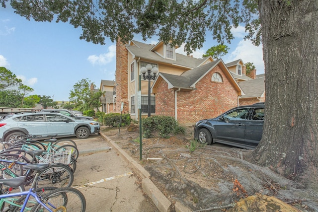 2300 Old Spanish Trl Unit 1060, Houston, TX 77054 - view of side of property featuring brick siding, uncovered parking, a chimney, and roof with shingles