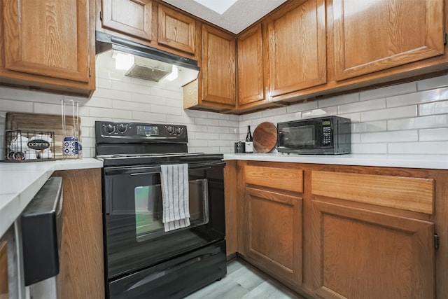 2300 Old Spanish Trl Unit 1060, Houston, TX 77054 - kitchen featuring black appliances, under cabinet range hood, brown cabinetry, and light countertops