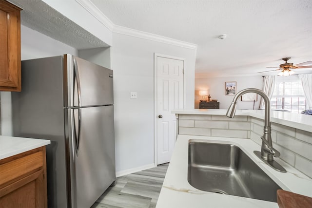 2300 Old Spanish Trl Unit 1060, Houston, TX 77054 - kitchen with freestanding refrigerator, brown cabinets, crown molding, light wood finished floors, and a ceiling fan