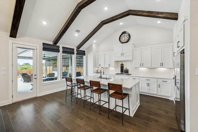 14115 Garibaldi Dr, Cypress, TX 77433 - kitchen with light countertops, a breakfast bar area, white cabinets, an island with sink, and backsplash