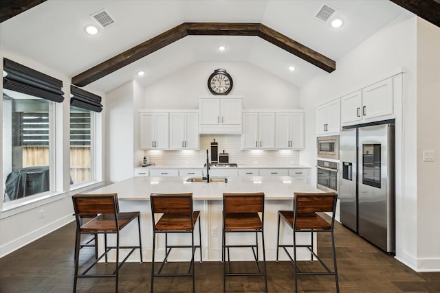 14115 Garibaldi Dr, Cypress, TX 77433 - kitchen featuring appliances with stainless steel finishes, light countertops, white cabinets, a kitchen bar, and beamed ceiling