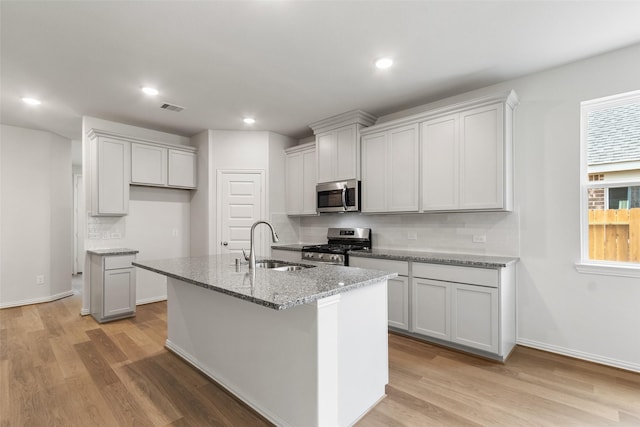 4402 Azalea Blossom Rd, Pinehurst, TX 77362 - kitchen featuring appliances with stainless steel finishes, light wood-style flooring, light stone countertops, an island with sink, and recessed lighting