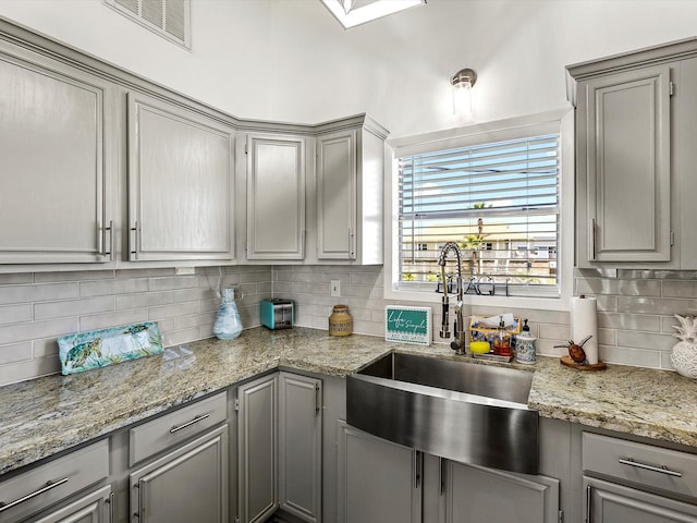 4039 San Jacinto Dr, Galveston, TX 77554 - kitchen with gray cabinetry, tasteful backsplash, and light stone countertops