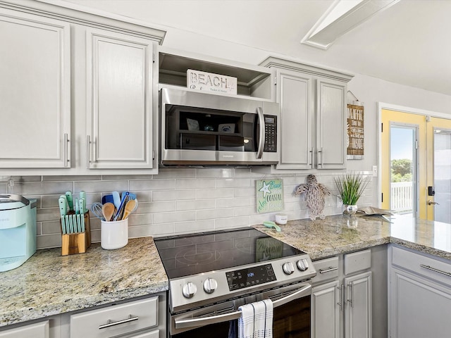 4039 San Jacinto Dr, Galveston, TX 77554 - kitchen featuring appliances with stainless steel finishes, backsplash, light stone counters, and a peninsula