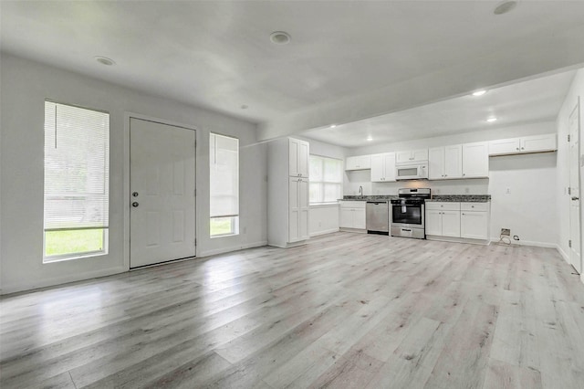 408 Commanche Rd, Conroe, TX 77316 - kitchen with stainless steel appliances, white cabinetry, light wood-style flooring, recessed lighting, and open floor plan