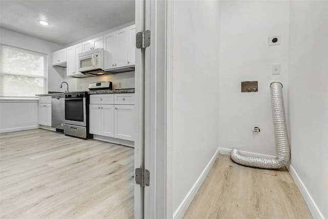 408 Commanche Rd, Conroe, TX 77316 - kitchen with stainless steel appliances, light wood-style floors, white cabinets, and dark countertops